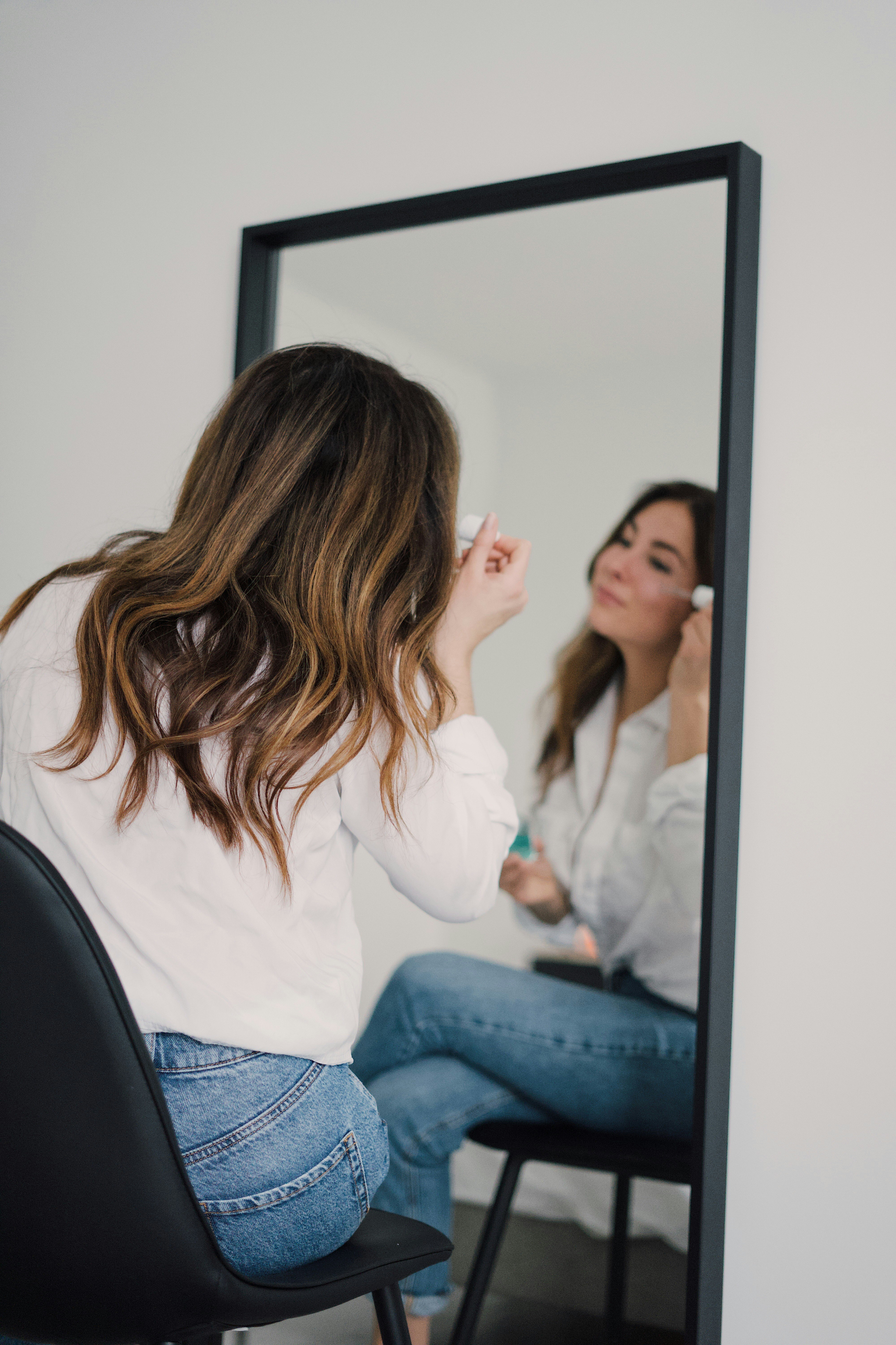 woman in white long sleeve shirt and blue denim jeans sitting on black chair